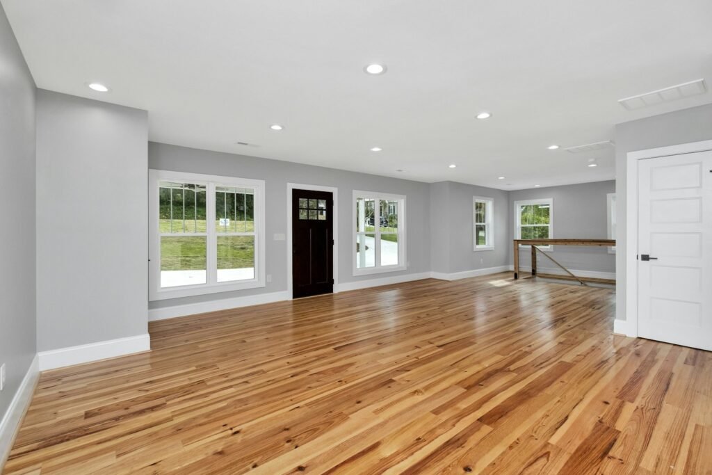 Empty room with hardwood flooring, light gray walls and large windows
